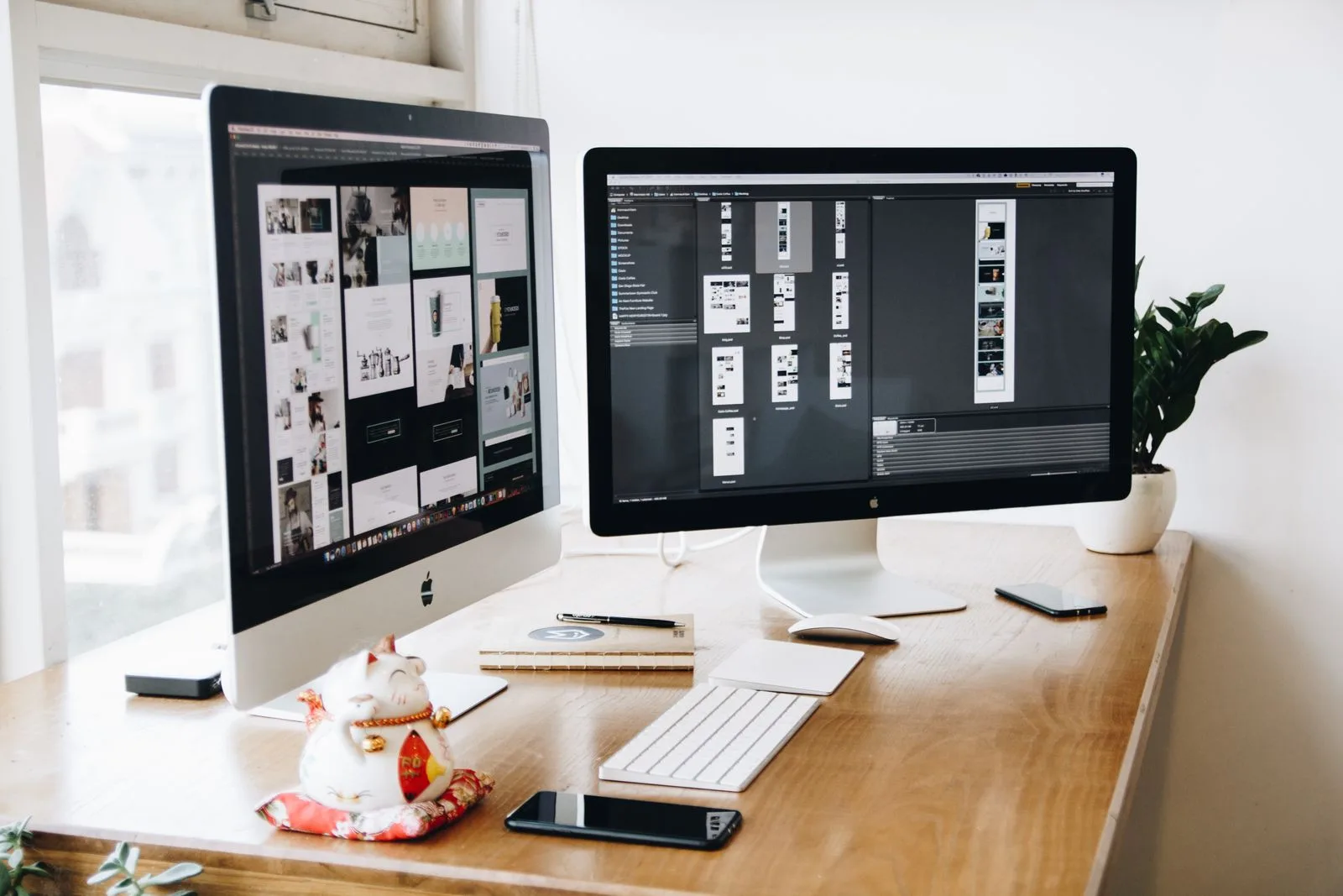Two desktop monitors displaying website layouts on a wooden desk