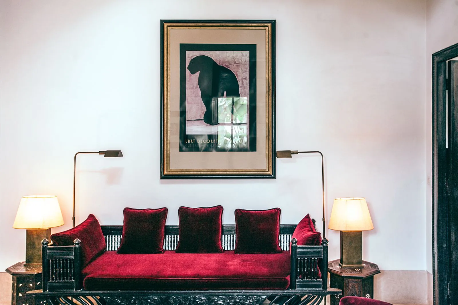 A red-cushioned sofa beneath a framed horse print, with table lamps on either side